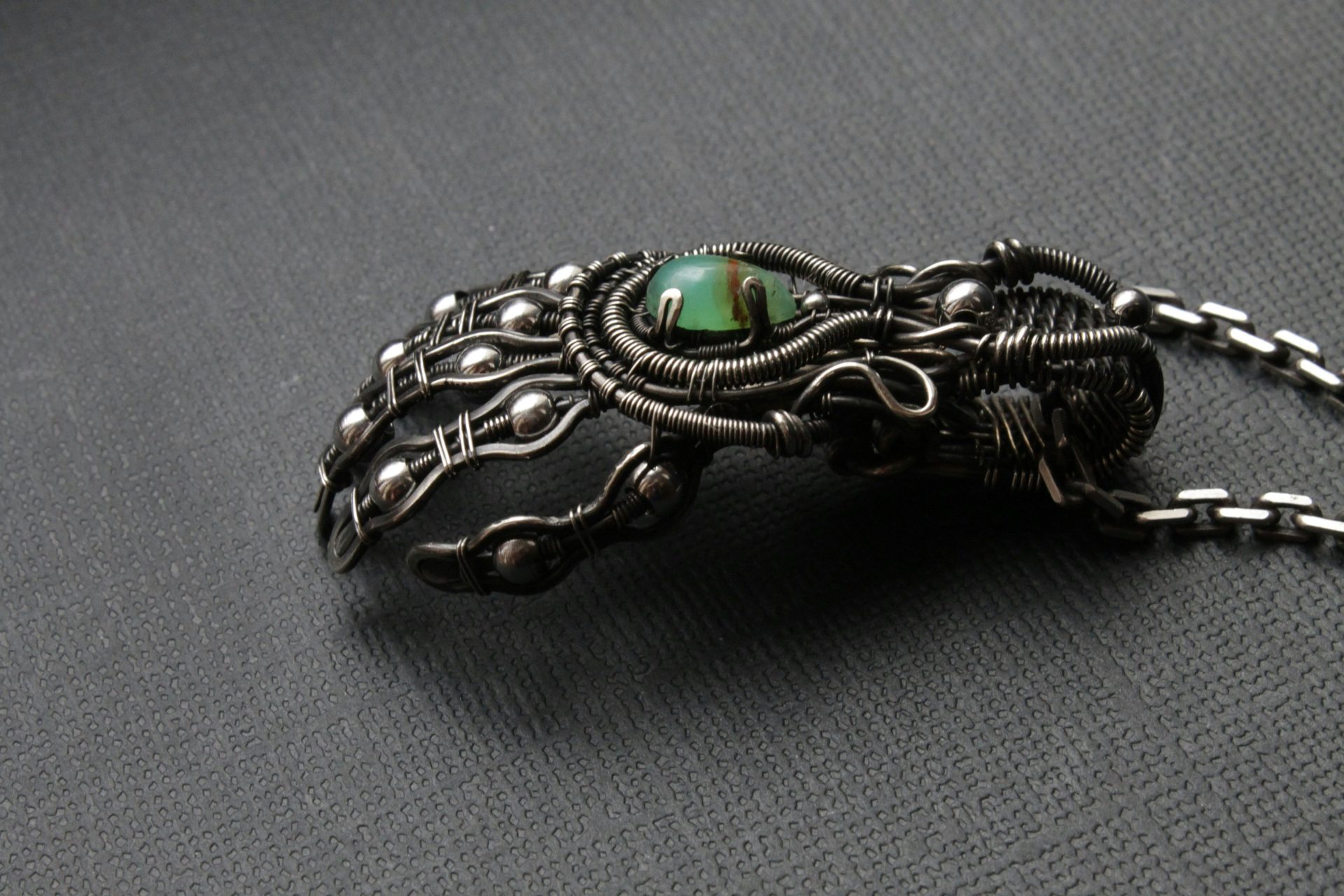 a close up of a brooch with a green stone