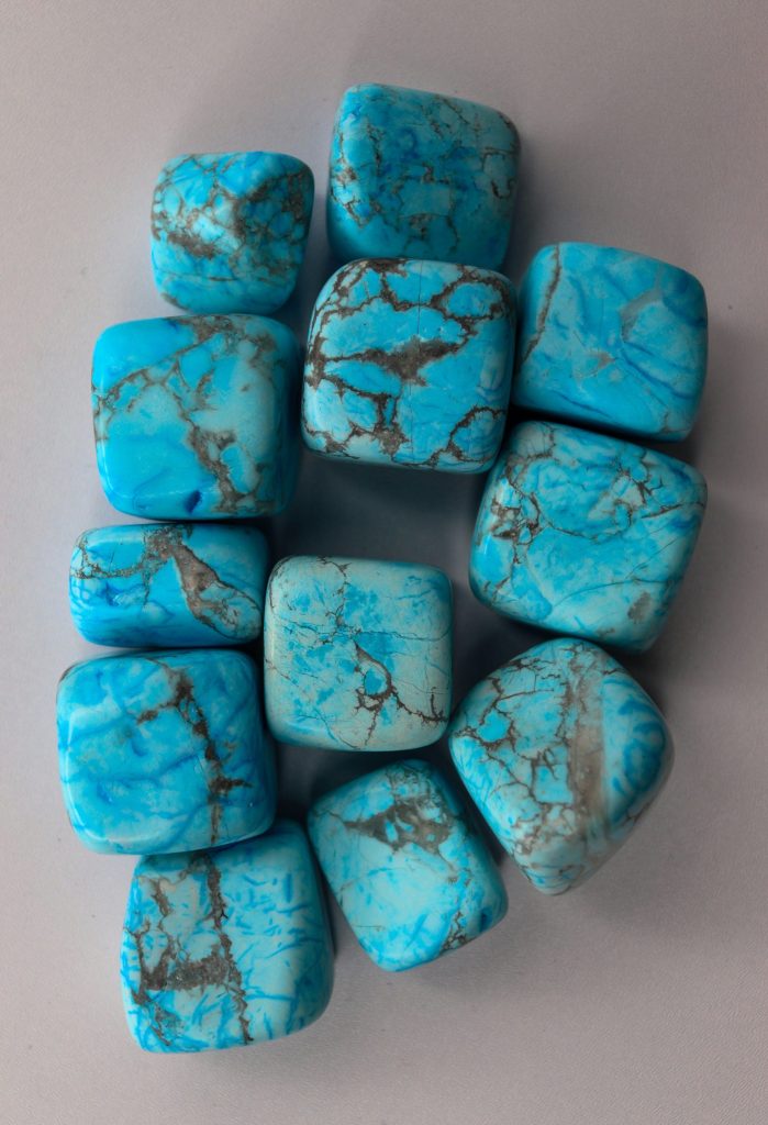 A collection of tumbled turquoise stones with dark veins.