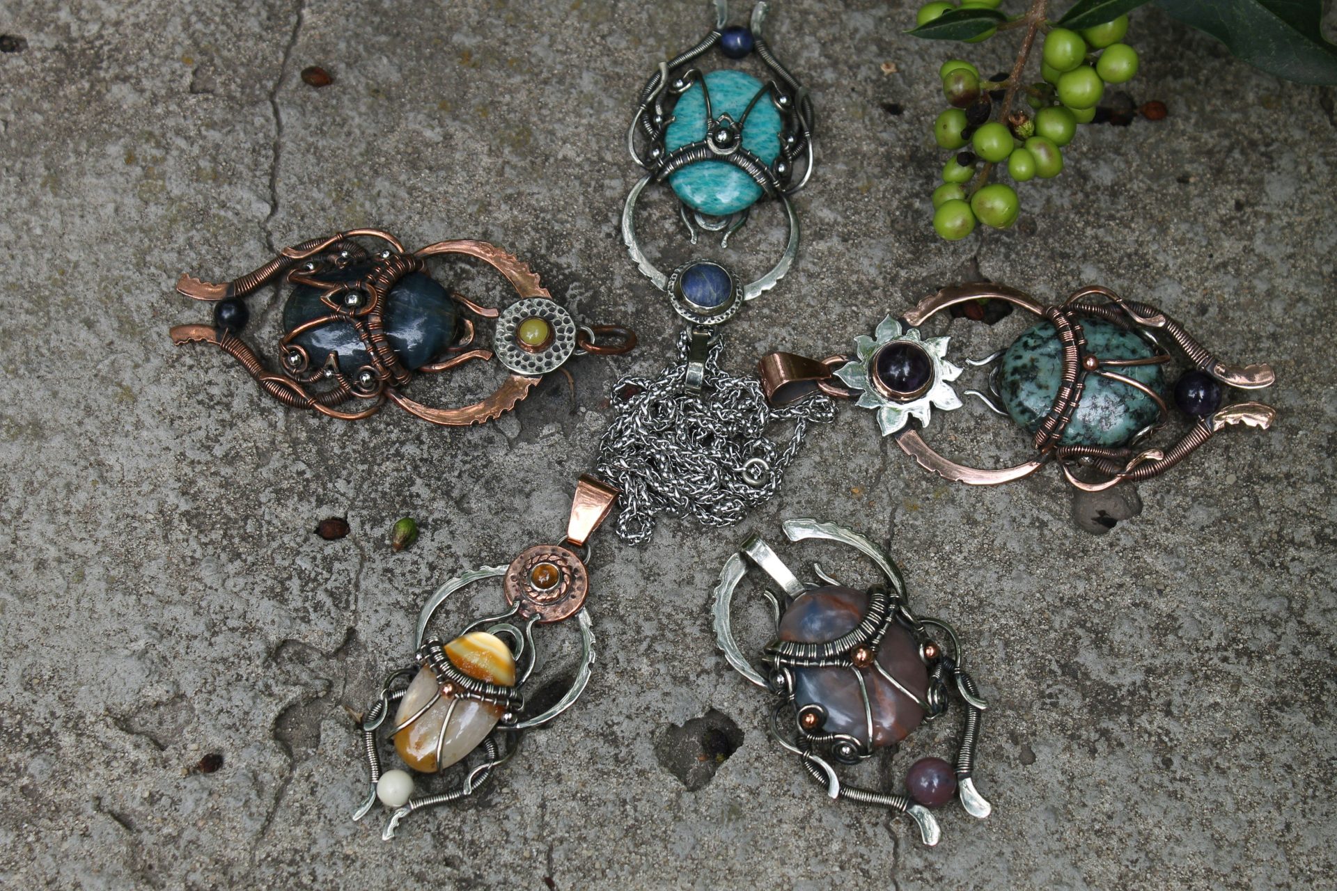 Five unique handcrafted pendants arranged in a star pattern.